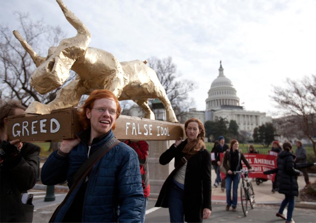 Students holding greed statue