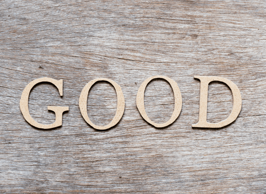 The word Good in gold colored wood against a wooden grain background