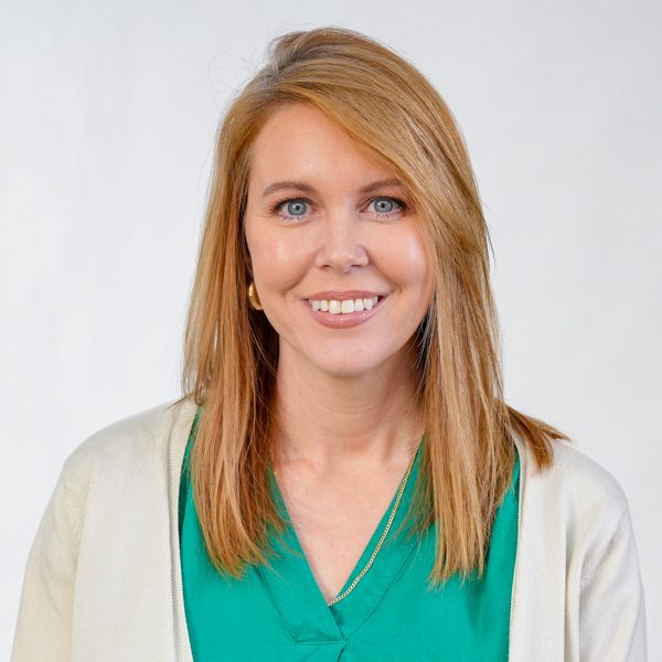  Professional headshot of Jennifer James, a woman with shoulder-length light brown hair, wearing a green V-neck blouse and a light-colored cardigan. She is facing the camera against a plain light gray background. The image is evenly lit and cropped from the chest up.